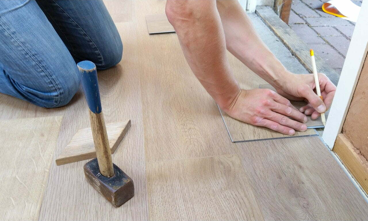 a person's hand holding a tool on a wood floor