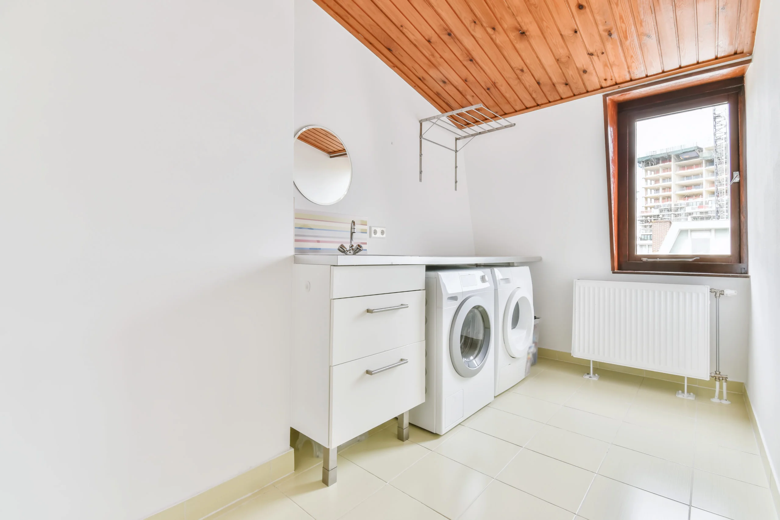 a white laundry room with a washing machine and a window