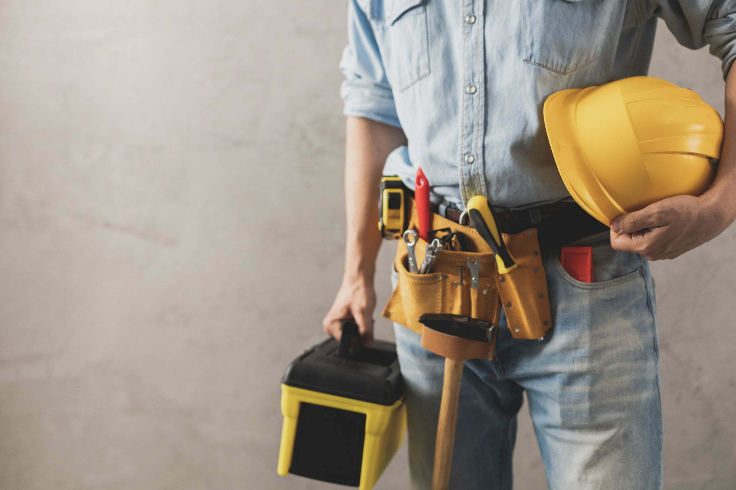 Worker holding construction helmet and toolbox