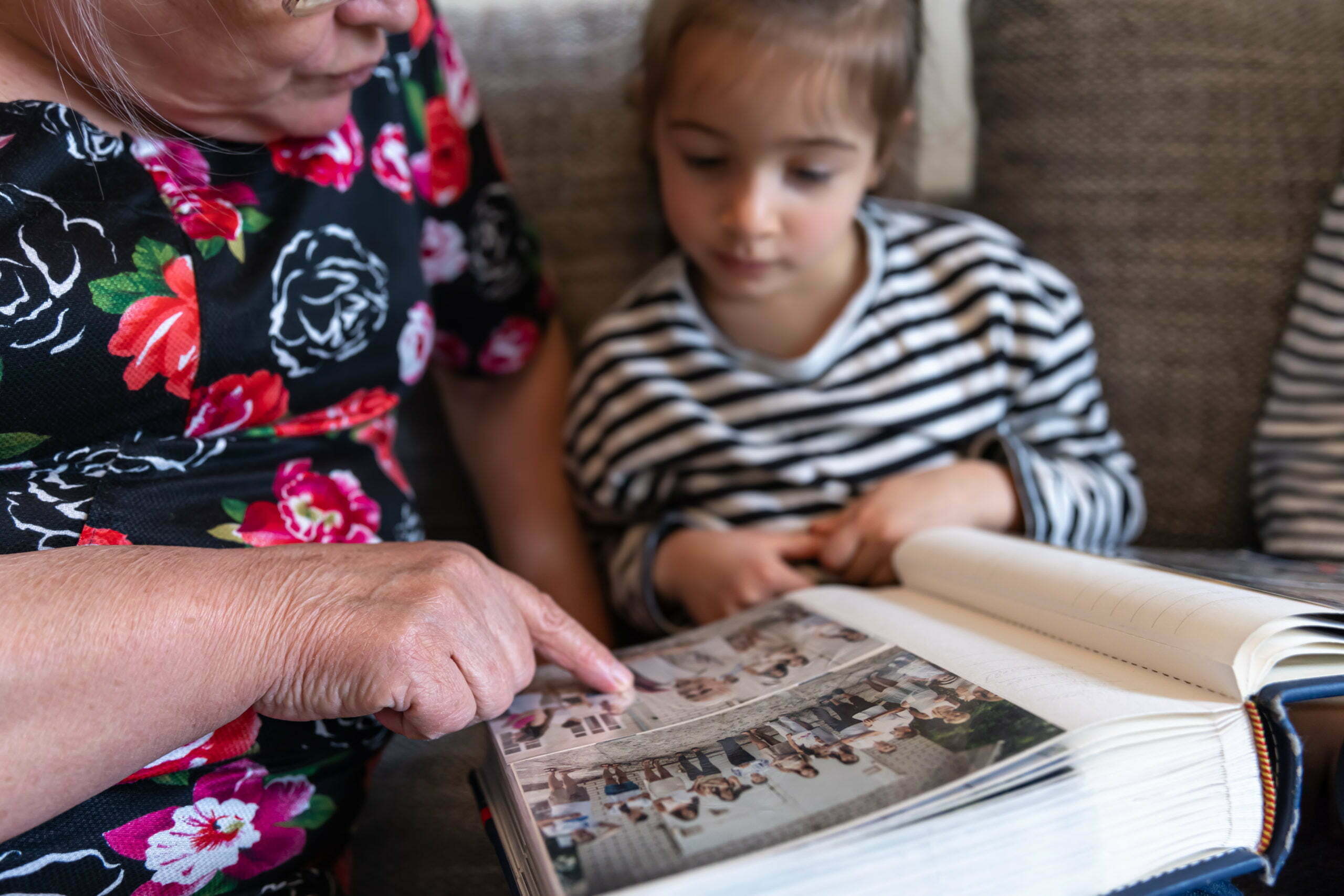 A grandmother with her granddaughter looking at a family photo album.